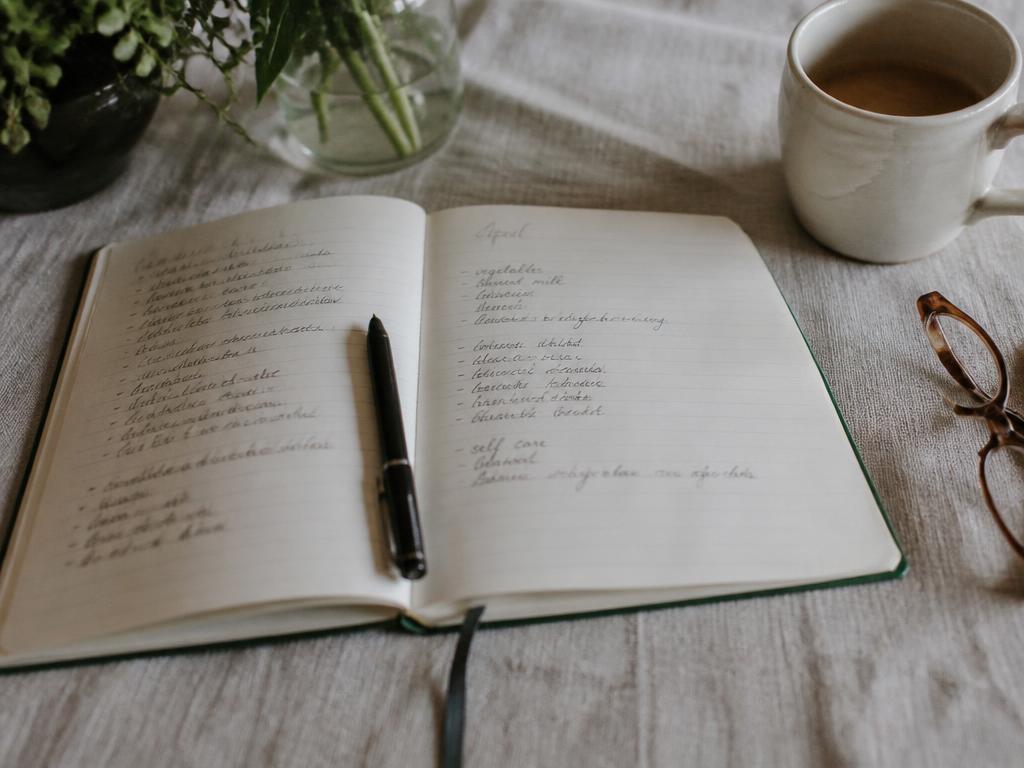 An open notebook and pen on linen beside a sprig of sage